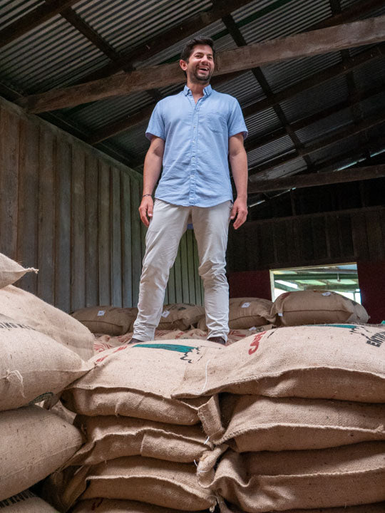 Farm manager, Diego Robelo stands proudly on a stack of burlap coffee bags ready for export at Aquiares Estate, Costa Rica.